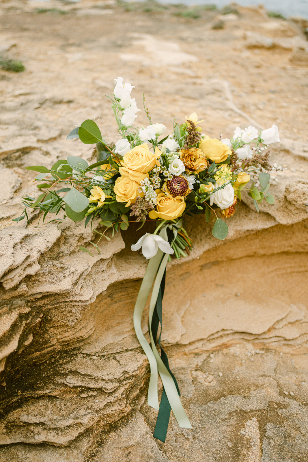 Brautstrauß mit gelben Blumen an einer Steinküste auf Mallorca