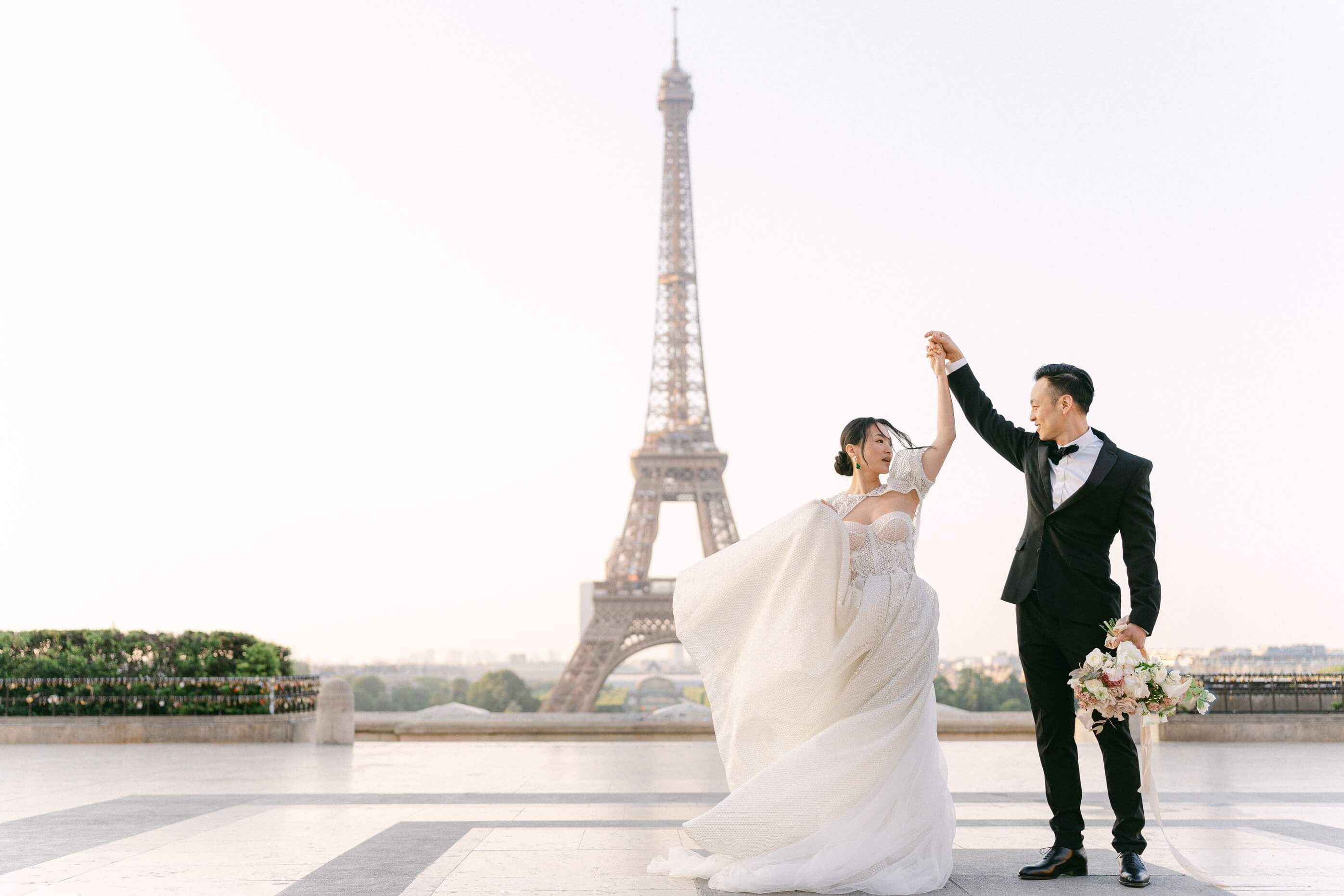 bride and groom dancing in front of the eiffel tower in paris wedding