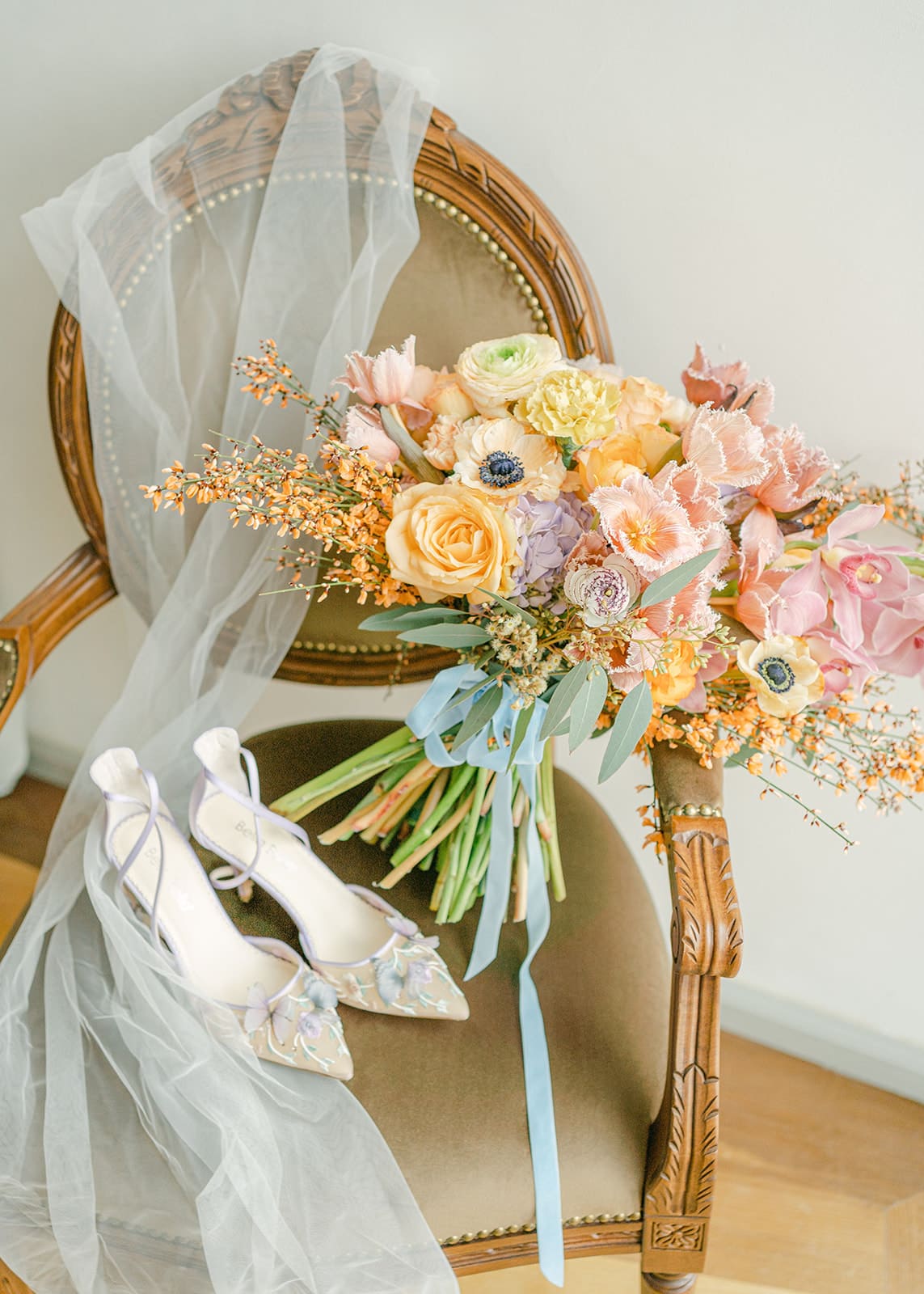 Beautiful vintage looking chair with colorful bridal bouquet, veil and bridal shoes from Bella Belle