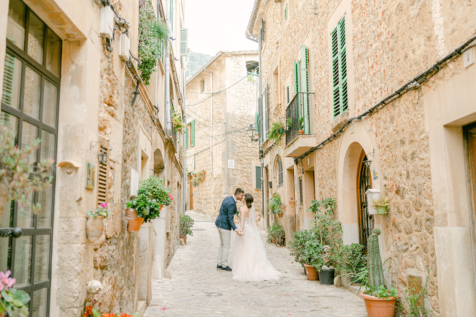 Brautpaarfoto von küssendem Hochzeitspaar auf Mallorca in einer Gasse in Valldemossa