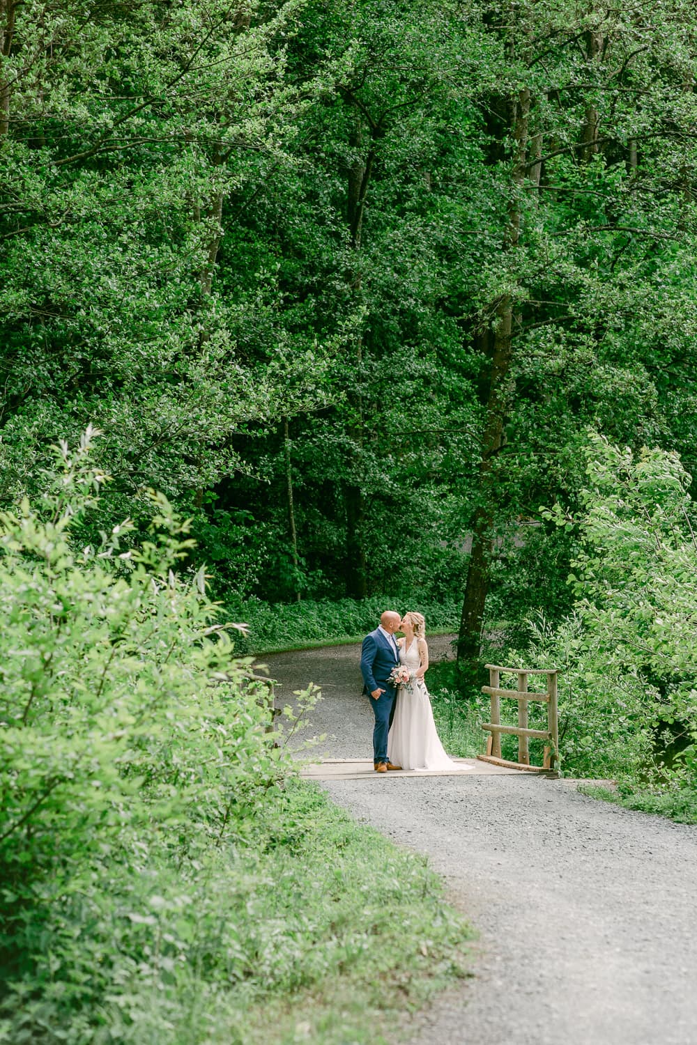 Foto von Hochzeitspaar auf Brücke im Wald