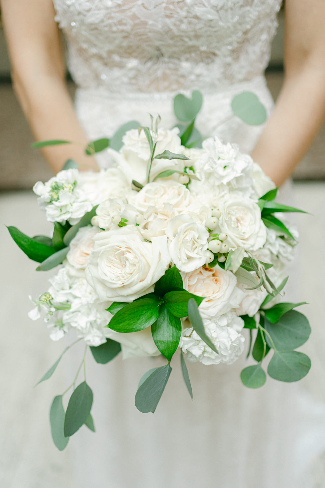 Detailfoto von Brautbouquet mit weißen Rosen und Braut im Hintergrund