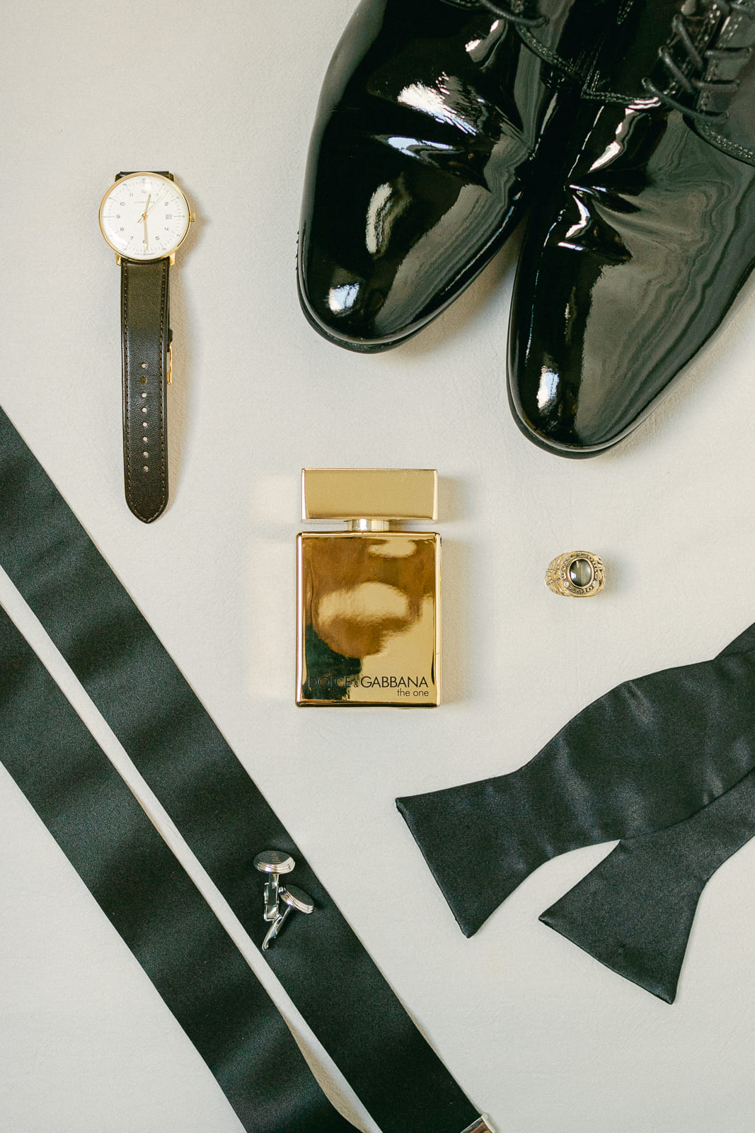 Flatlay wedding photo of groom getting ready with perfume, watch, ring, shoes, bow tie, cufflinks