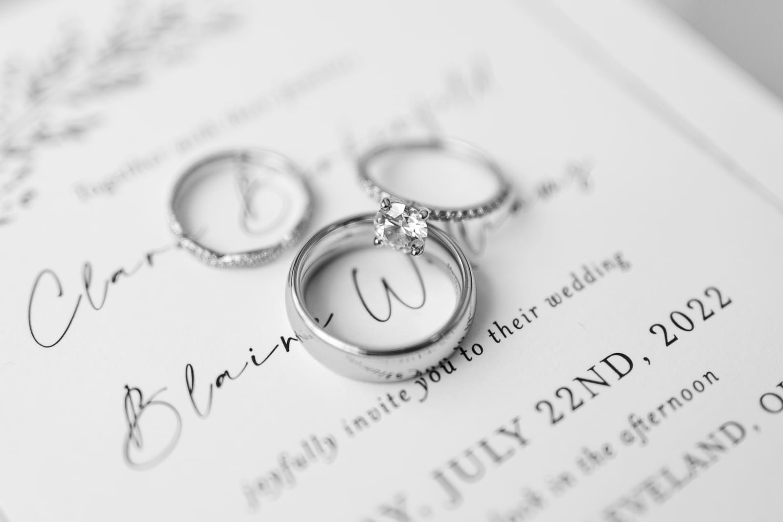 Detail photo of wedding rings and engagement ring on wedding invitation in black and white
