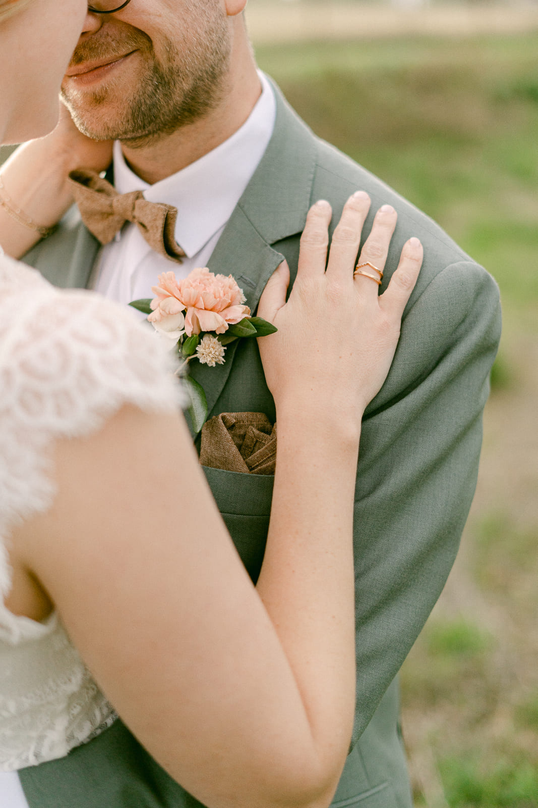 Detailfoto von Hochzeitspaar Hand der Braut mit Eheringen auf Brust von Braeutigam